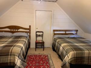 a attic bedroom with two beds and a chair at Va Beach Zen tree house style studio F in Virginia Beach