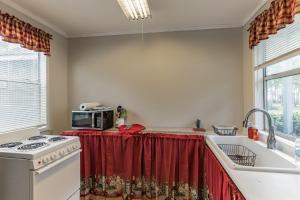 uma cozinha com um fogão e uma cortina vermelha em Pura Vida East Point with Bay View em Eastpoint