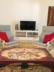 a living room with two chairs and a tv at Bukit Indah Boutique Accommodation in Selong Belanak