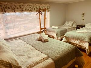 1 dormitorio con 2 camas y ventana en Arte Brisa Hostal Boutique, en Puerto Natales