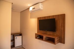 a hotel room with a television and a air conditioner at Vila da Mata Chalés in Alto Paraíso de Goiás