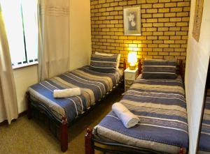 two beds in a room with a brick wall at Geraldton Beachfront Villas in Geraldton
