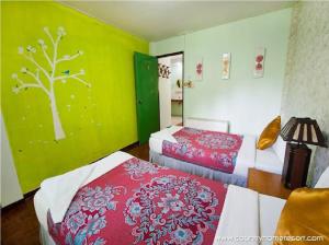 a bedroom with two beds and a green wall at Huaykhakhaeng Country Home Resort in Ban Rai