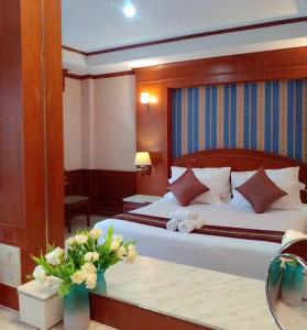 una habitación de hotel con una cama con flores en una mesa en The Lion King Hotel Udonthani, en Udon Thani