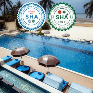 a swimming pool with blue chairs and umbrellas next to it at Dhevan Dara Beach Villa Kuiburi in Kui Buri