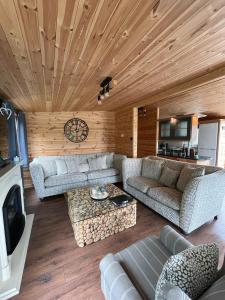 uma sala de estar com sofás e um relógio no tecto em Percy Wood Lodges with Hot Tubs em Swarland