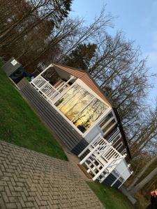 una pequeña casa con sillas blancas en el patio en Percy Wood Lodges with Hot Tubs en Swarland