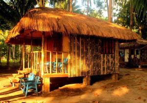 Cabaña pequeña con sillas y techo de paja en Arkadia Beach Resort by RedDoorz, en Sabang