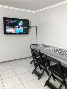 Habitación con mesa y TV en la pared. en Unidade independente em sobrado, confortável e familiar no coração de Foz! TÉRREO en Foz de Iguazú