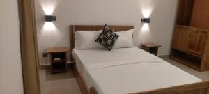 ein Schlafzimmer mit einem weißen Bett und zwei Kissen in der Unterkunft AZURIA HOTEL in Lomé