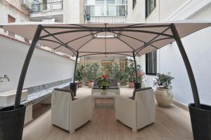 een patio met een tafel en stoelen onder een grote parasol bij Meridiana B&B in Palermo