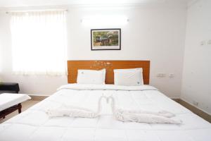 a white bedroom with a large white bed with white sheets at Hotel TamilNadu - Yercaud in Yercaud +3 photos