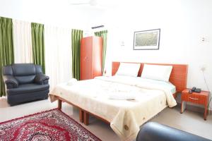 a bedroom with a large bed and a chair at Hotel TamilNadu - Yercaud in Yercaud