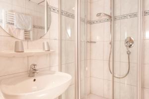 a white bathroom with a sink and a shower at Landhaus Tannheimer in Oberstdorf +12 photos