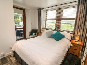 a bedroom with a large white bed and windows at The Lodge in Ulverston
