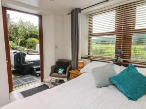 a bedroom with a bed and a chair and a window at The Lodge in Ulverston