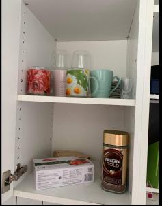 une étagère avec des tasses et une boîte de café dans l'établissement Kumpukuja apartment, à Kouvola