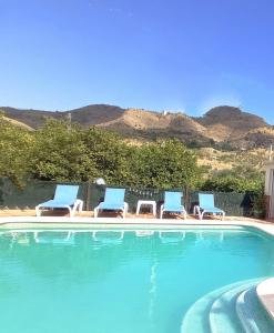a group of chairs and a swimming pool with mountains at Casa rural la Estrella in Pizarra
