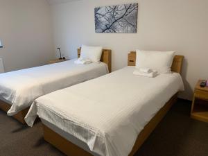 two beds in a room with white sheets at Momiji Montana in Furano