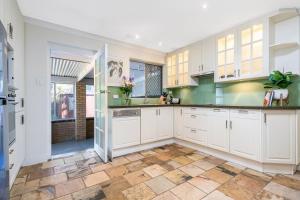 uma cozinha com armários brancos e piso em azulejo em Layman Park Villa em Perth