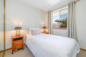 a bedroom with a white bed and a window at Layman Park Villa in Perth