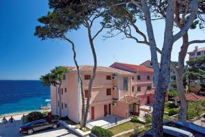 a large pink building next to the ocean at Apartment in Veli Losinj by the Beach in Veli Lošinj