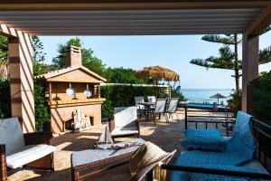 une terrasse avec des chaises, une cheminée et l'océan. dans l'établissement Beachfront Andriana Villa with mini pool and spa, à Vasilikos