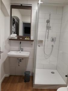 ein Bad mit einer Dusche und einem Waschbecken in der Unterkunft Urban Flair Hotel in Memmingen