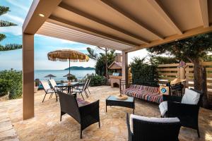 a patio with a couch and a table and chairs at Beachfront Elena Villa with mini pool and spa in Vasilikos
