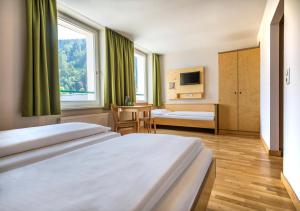 a hotel room with two beds and a window at JUFA Hotel Schladming in Schladming