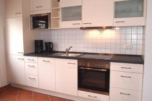 eine Küche mit weißen Schränken und einem Waschbecken in der Unterkunft Residenz an der Prorer Wiek Ferienwohnung 09 in Binz