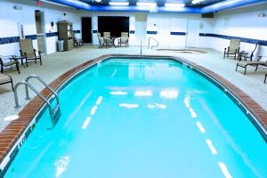 a large swimming pool in a hotel room with chairs and tables at Holiday Inn Express Hotel & Suites Pierre-Fort Pierre by IHG in Fort Pierre