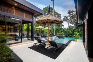 eine Außenterrasse mit Stühlen und Sonnenschirm und ein Swimmingpool in der Unterkunft Villa Singa by BaliSuperHost in Ubud