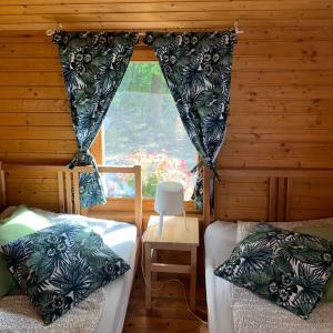 Habitación con 2 camas y ventana en una cabaña en VÁR-CAMPING, en Sirok