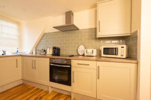 kuchnia z białymi szafkami i kuchenką mikrofalową w obiekcie Stylish City Apartment - Prime Location! w Nottingham