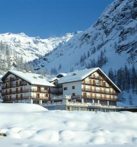 a hotel in the snow with a mountain at La Trinitè Monboso Hotel in Gressoney-la-Trinité