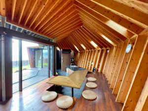 a wooden room with a bench and stools on the floor at Seaside SHELL HOUSE -南房総 海辺のSHELL HOUSE- in Minamiboso