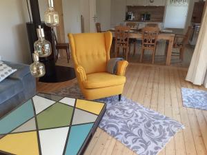 ein Wohnzimmer mit einem gelben Stuhl und einem Tisch in der Unterkunft Ferienhaus Wiesenblick in Monschau