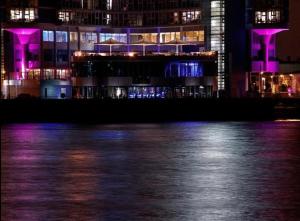 a building with purple lights on the water at night at Rafayel Hotel & Spa in London