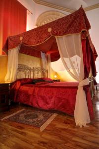 a bedroom with a red bed with a canopy at Antica Corte delle Ninfee, Historical Private Villa in Trapani