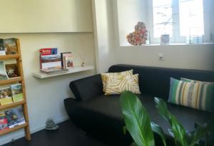 a living room with a black couch and a window at Relais du Simplon in Conthey