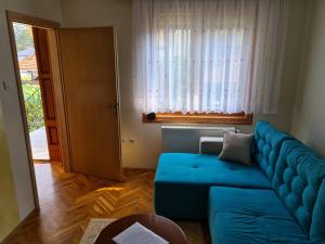 a living room with a blue couch and a window at Apartman Bubamara in Arilje