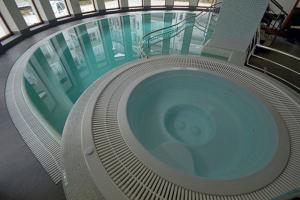 a large swimming pool in a building with a glass floor at Apartament Stara Polana i Spa in Zakopane