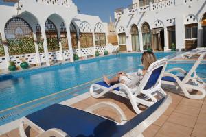 a little girl sitting in a chair next to a swimming pool at Kuwait Palace Hotel in Kuwait