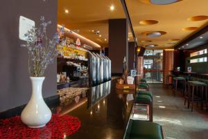 - un bar avec un vase blanc sur une table et des chaises dans l'établissement Hotel Prunk, à Sežana