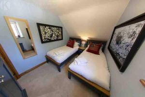 a small room with two beds and a mirror at The Old Manor Coach House in Cirencester
