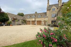 a large stone house with a large driveway at The Old Manor Coach House in Cirencester