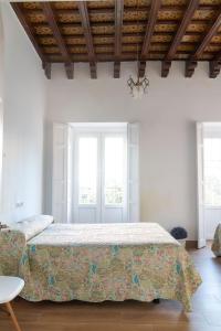 a bedroom with a large bed and two windows at Apartamentos El Alcazar de Jerez in Jerez de la Frontera
