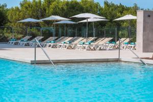 a swimming pool with lounge chairs and umbrellas at Iberostar Waves Cala Millor - Adults Only in Cala Millor