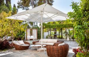 eine Terrasse mit einem weißen Sonnenschirm, Stühlen und Tischen in der Unterkunft Lear Sense Hotel in Gedera
